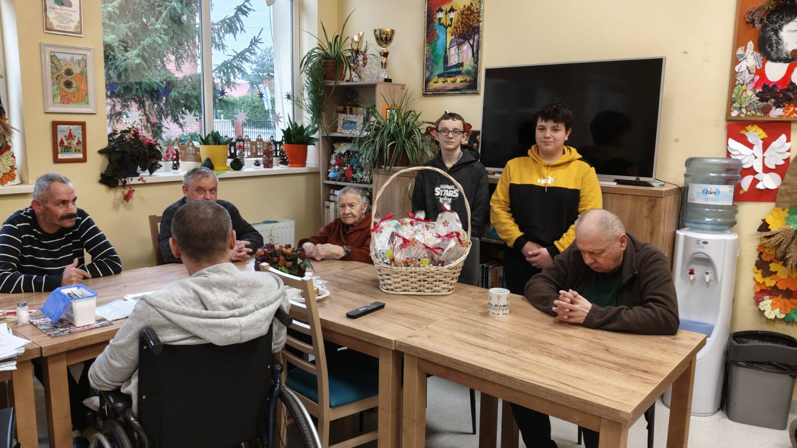 Dzieci z prezentem seniorzy przy stole