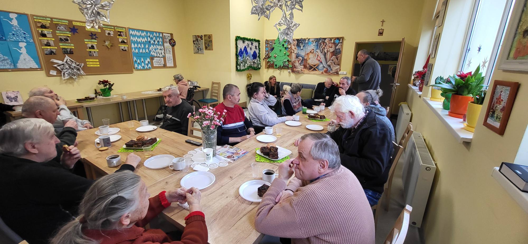 Mieszkańcy DPSu przy stole rozmawiają pijąc kawę 