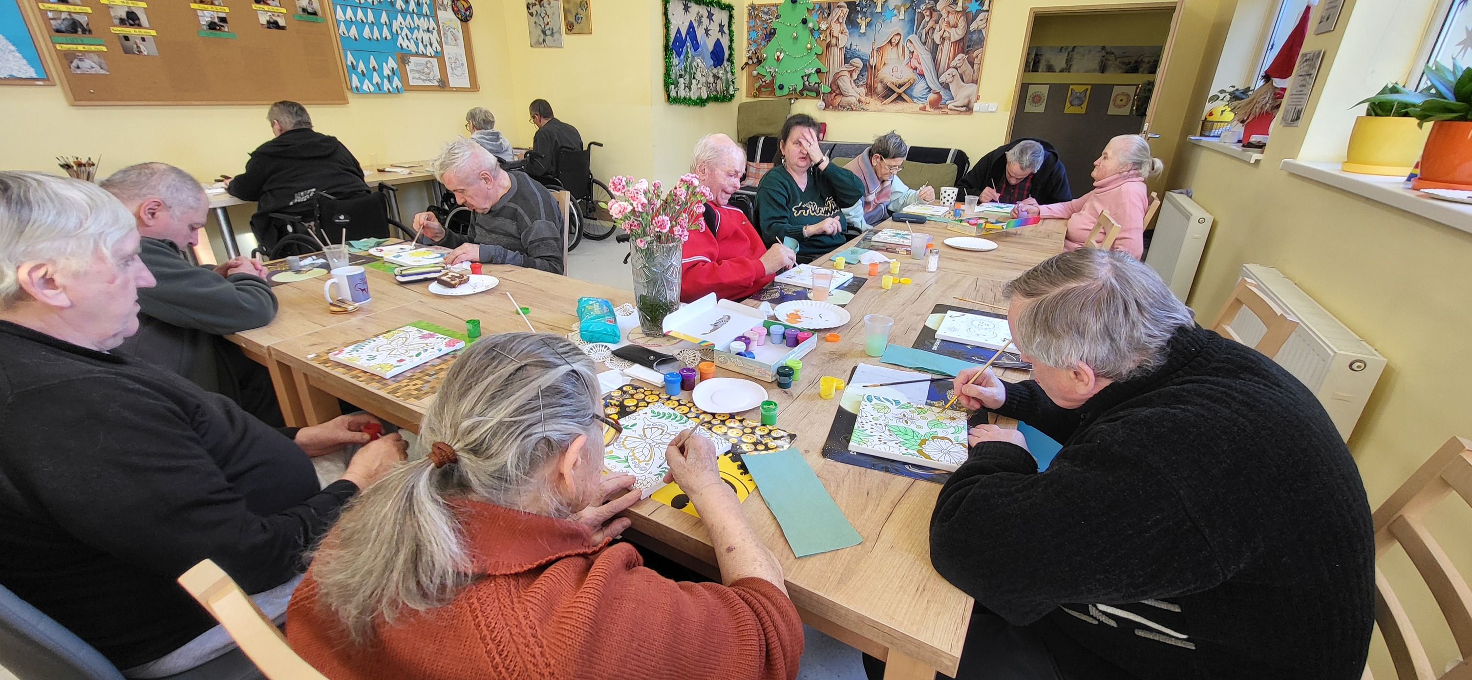 Mieszkańcy DPSu przy stole zajęcia kreatywne