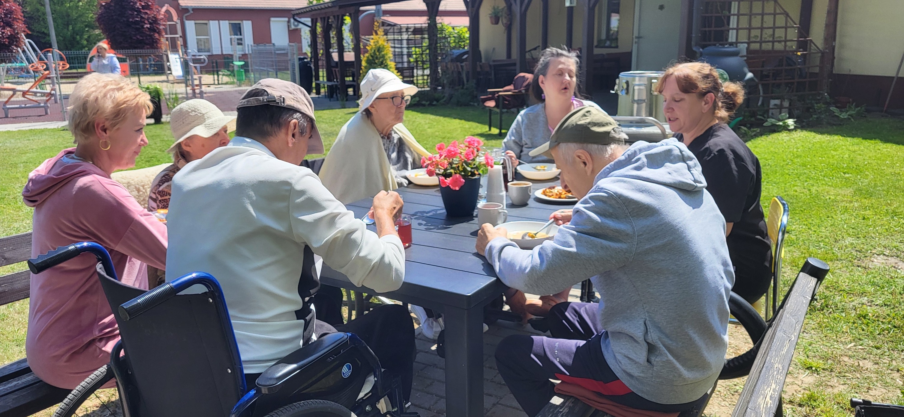 seniorzy przy stole jedzą lunch na swiezym powietrzu 