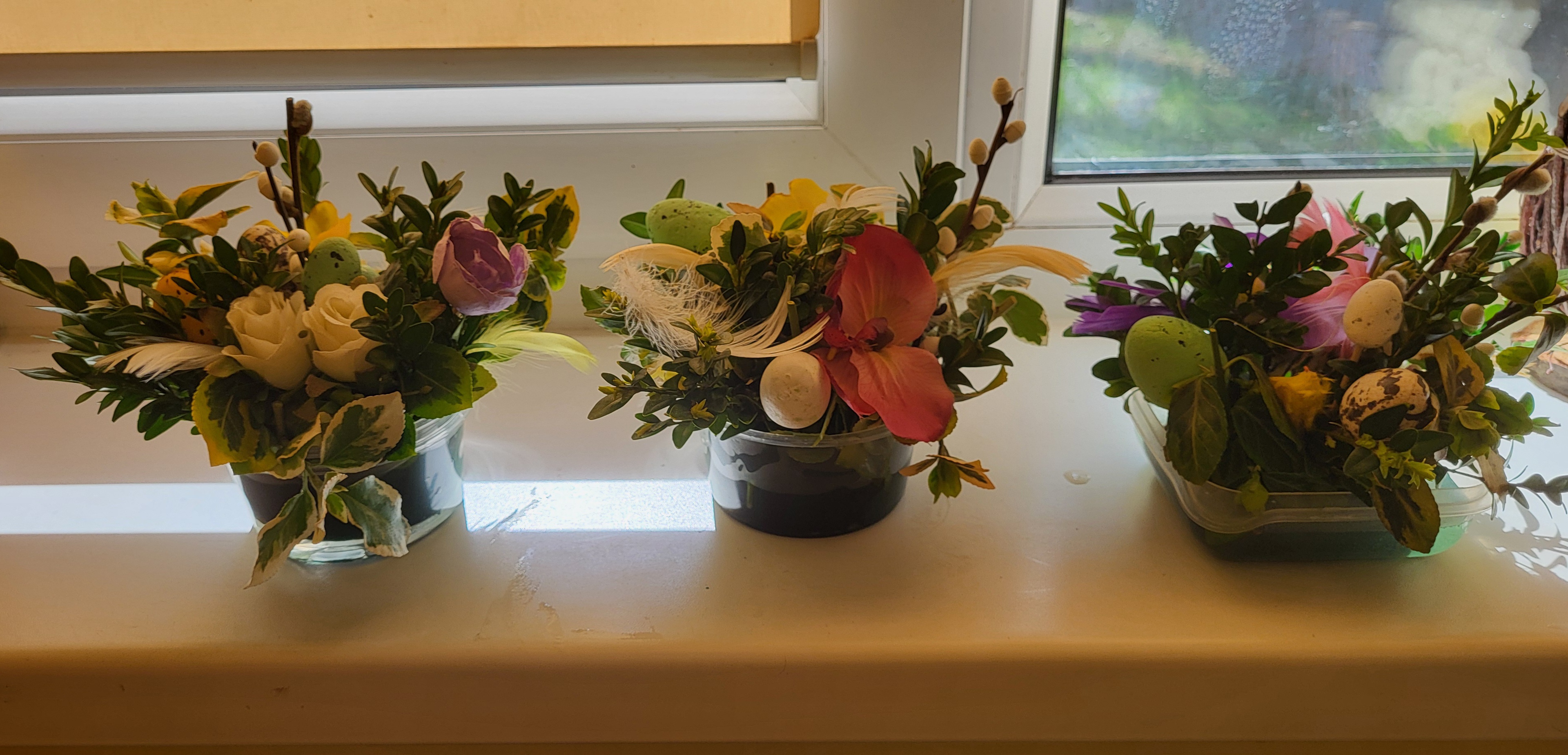 Dekoracje wielkanocne stojące na parapecie. Różne kolorowe kwiaty